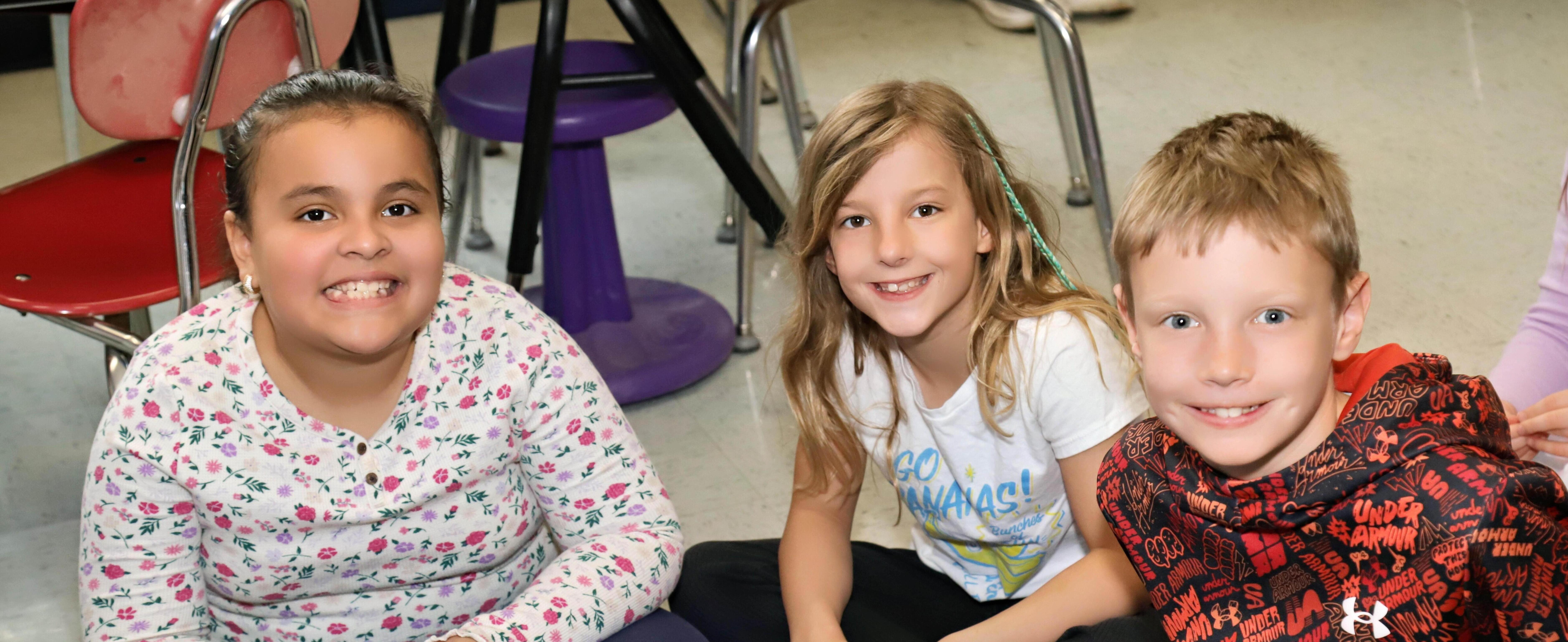 Three students sitting on a rug