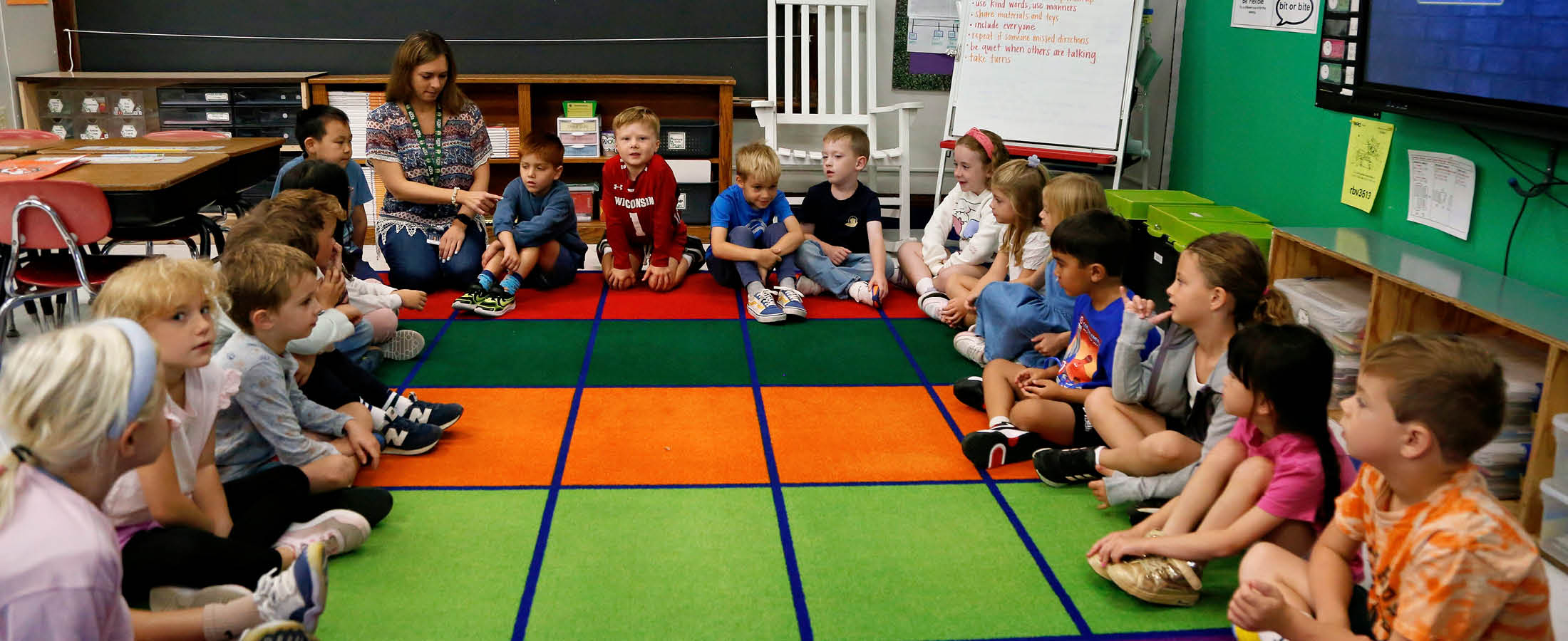 Students and teacher sitting on rug