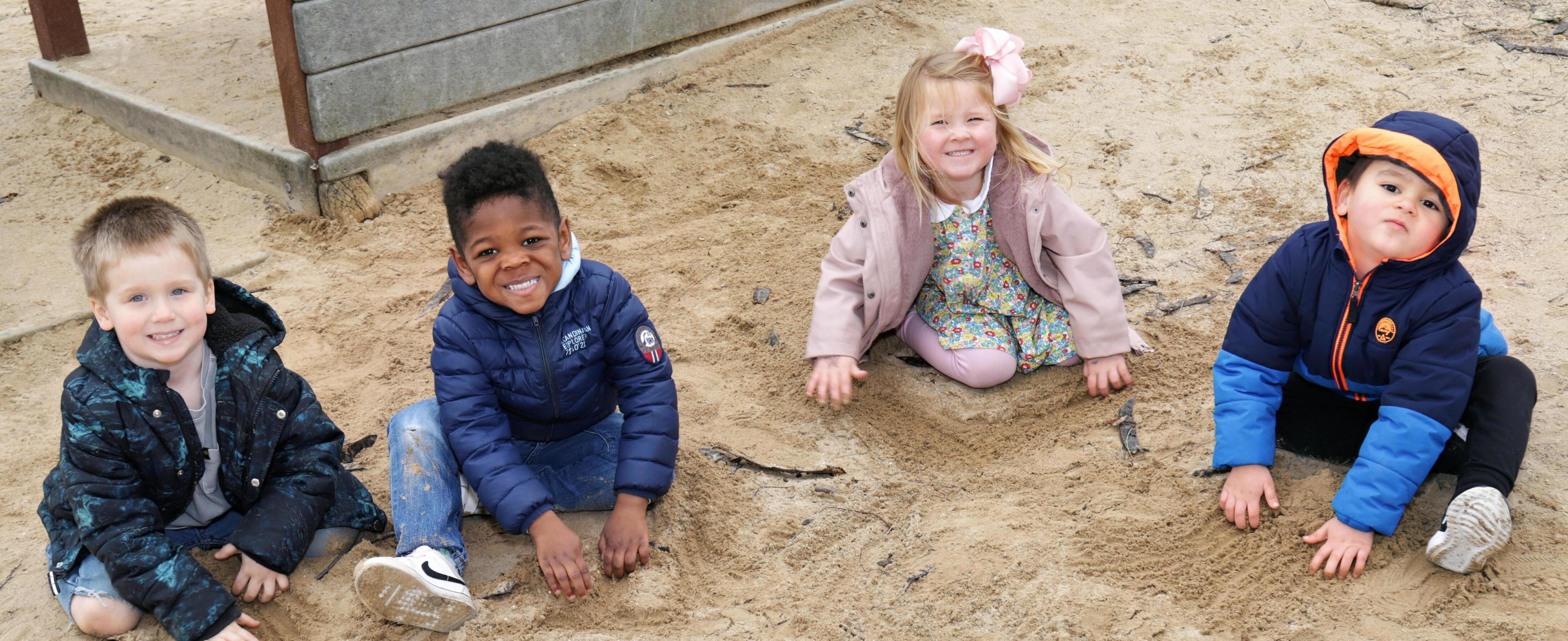 Four students playing in the sand